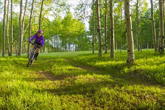 Hispanic teenager riding bicycle in woods