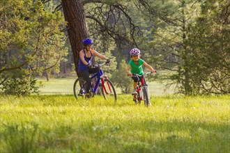 Mother and daughter riding mountain bikes in meadow