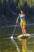 Hispanic woman riding paddle board