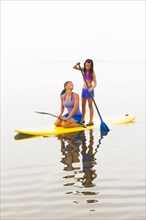 Mother and daughter riding paddle board