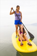Mother and daughter riding paddle board