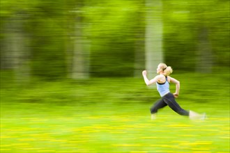 Blurred view of Caucasian woman running in tall grass