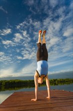 Caucasian woman practicing yoga on dock on still lake