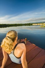 Caucasian woman relaxing on dock on still lake