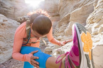 Woman stretching leg in canyon wearing backpack