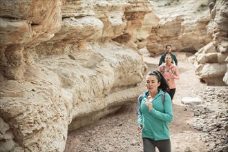 Women running in canyon wearing backpacks