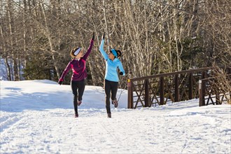 Women running and celebrating on snow in winter