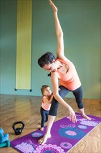 Mixed Race expectant mother practicing yoga and watching daughter