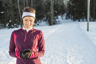 Caucasian runner listening to cell phone with earbuds in winter
