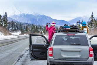 Caucasian women photographing from car with snowboards