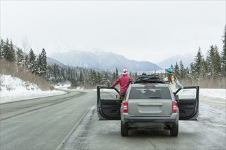 Caucasian women standing in car in winter admiring scenic view