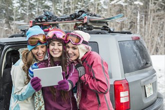 Women posing for cell phone selfie in winter using digital tablet