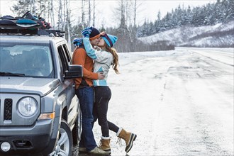 Caucasian couple kissing near car in winter