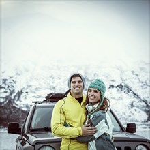 Caucasian couple hugging near car in winter