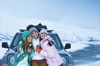 Women hugging near car in winter