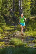 Hispanic woman running on wet trail