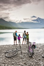 Couple with son and daughter riding bicycles near lake