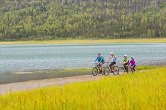 Couple with son and daughter riding bicycles near lake