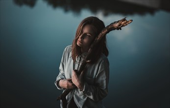 Caucasian woman holding stick near still lake