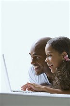 Mixed race father and daughter using laptop