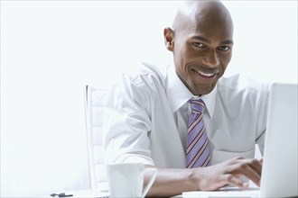 Mixed race businessman using laptop at desk