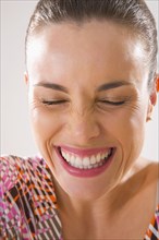 Mixed race woman smiling and grimacing with eyes closed