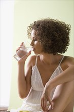 Mixed race woman drinking glass of water