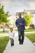 Father and son running on sidewalk