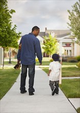 Father and son walking with baseball glove and bat
