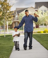 Father and son walking with baseball glove and bat