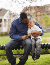 Father and son sitting together on park bench