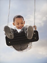 Mixed race boy swinging