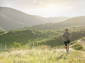 Caucasian man running on remote hill
