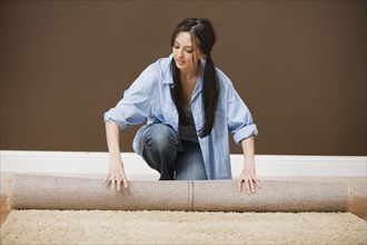 Caucasian woman unrolling carpet