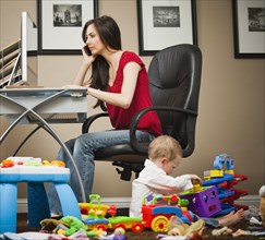 Caucasian woman tending child and working in home office