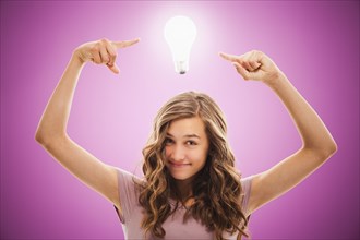 Caucasian teenager pointing at light bulb over her head