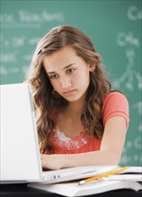 Caucasian teenager using laptop in classroom