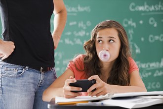 Frustrated teacher watching student with cell phone and gum