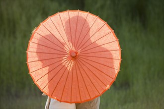 Caucasian couple standing behind parasol