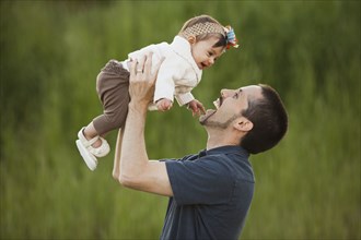 Caucasian father lifting daughter outdoors