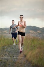 Caucasian couple running together on remote path