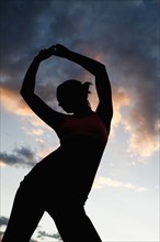Caucasian woman stretching before exercise at sunset