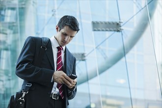 Caucasian businessman text messaging on cell phone outdoors