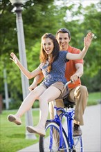 Caucasian couple riding bicycle together