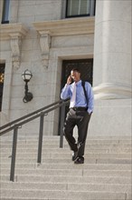 Black businessman talking on cell phone and walking down stairs