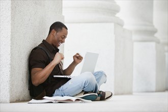 Black college student using laptop outdoors