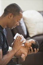 Father feeding bottle to newborn baby
