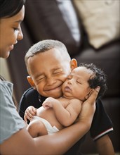 Mixed race boy hugging newborn baby