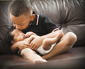 Mixed race boy kissing newborn baby