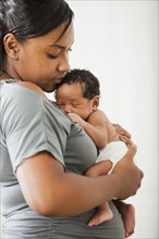 Mixed race mother holding newborn baby